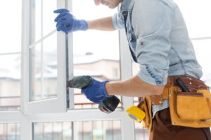 Construction worker installing window in house. Handyman fixing the window with screwdriver.